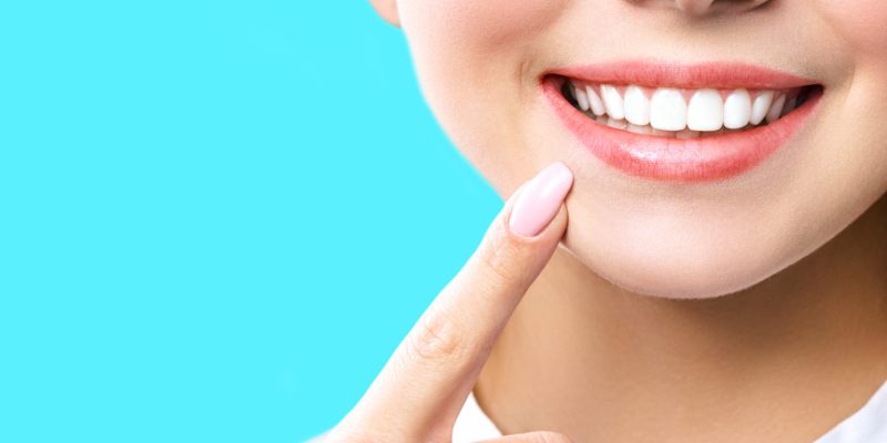 Perfect healthy teeth smile of a young woman. Teeth whitening. Dental clinic patient. Image symbolizes oral care dentistry, stomatology. blue Background.